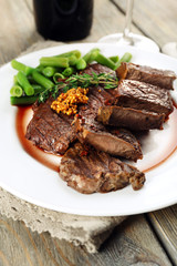 Steak with wine sauce on plate on wooden table