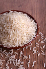 Grain of rice on plate on wooden background