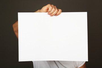 Fototapeta premium Blank sheet of paper in male hand on dark background
