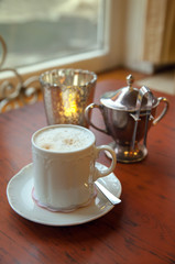 White mug of cappuccino on the table in a cafe