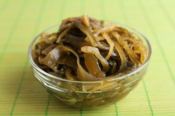 Seaweed in glass bowl on bamboo mat background