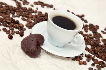 The cup of coffee and small gingerbread in shape of heart