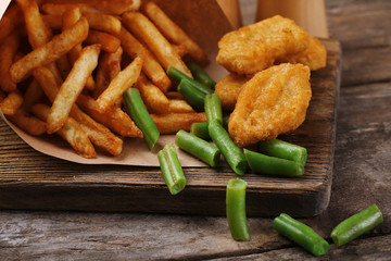 Breaded fried chicken nuggets and potatoes in paper bag with
