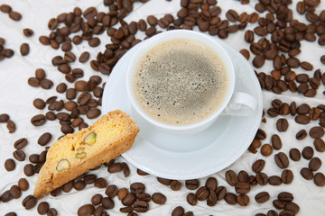 The white mug of american coffee with piece of biscotti