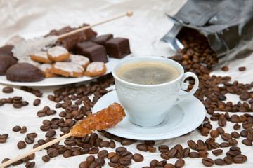 The coffee cup with caramel stick and dish of chocolate sweets