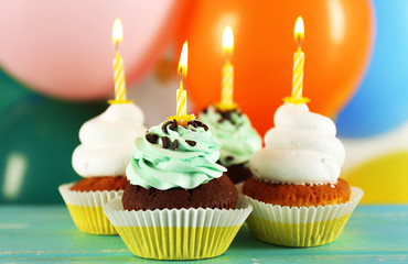 Delicious birthday cupcakes on table on bright background