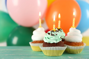 Delicious birthday cupcakes on table on bright background