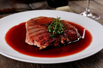 Grilled steak in wine sauce on plate on table close up