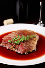 Grilled steak in wine sauce with bottle of wine