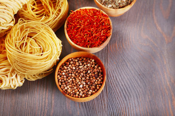 Different dry instant noodles with spices on wooden background
