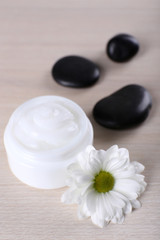 Fototapeta na wymiar Cosmetic cream with spa stones and chamomile