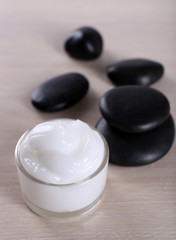 Fototapeta na wymiar Cosmetic cream with spa stones on wooden background