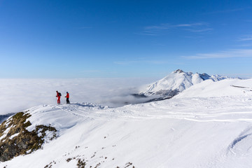 Fototapeta na wymiar Two skiers on top of mountain above the clouds