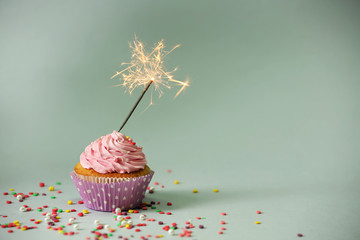 Cupcake with sparkler on grey background