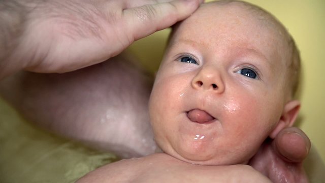 Washing newborn baby in bathtub
