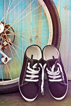 Shoes and a bicycle wheel on a background of blue wooden fence.