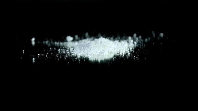 White pouder falls onto the table on black surface
