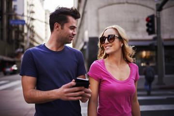 romantic couple with smartphone walking through los angeles