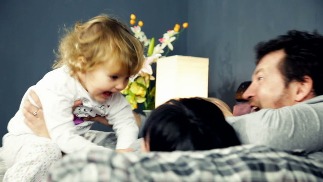 Happy family playing in bed having fun