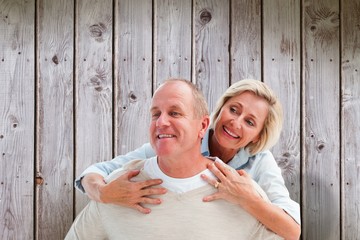 Composite image of happy mature man giving piggy back to partner
