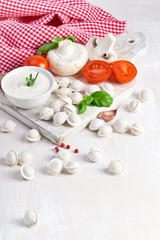 Tortellini and vegetables on white wooden background