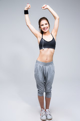 smiling sporty woman stretching leg over gray background