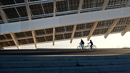 Dos ciclistas paseando debajo de la placa solar del Forum de Barcelona típica Arquitectura urbana...