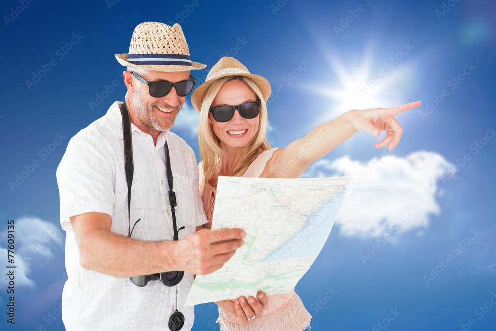 Aufkleber Composite image of happy tourist couple using map and pointing