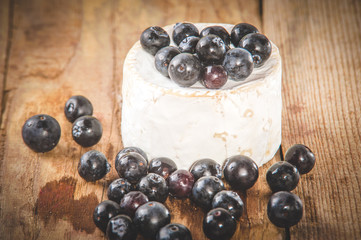 Smelly blue cheese on a wooden rustic table with blueberries