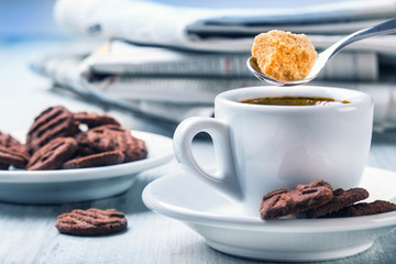 Cup of coffee spoon with cane sugar, chocolate biscuits and the 