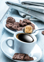 Cup of coffee spoon with cane sugar, chocolate biscuits and the 