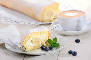 Kaffeegedeck mit Sahnerolle und Cappuccino