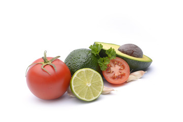 Fresh avocado surrounded by  tomato, garlic and lime on white background