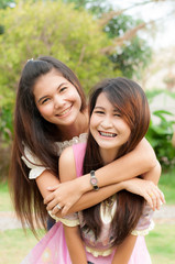 Asian sisters friends embracing and laughing at camera