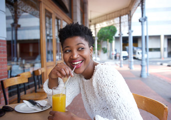 Happy african american woman drinking orange juice