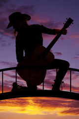 silhouette cowgirl kneel with guitar look back
