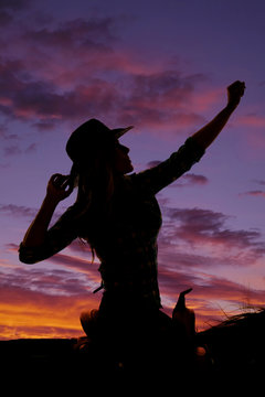 silhouette of a cowgirl on a saddle hand up and out
