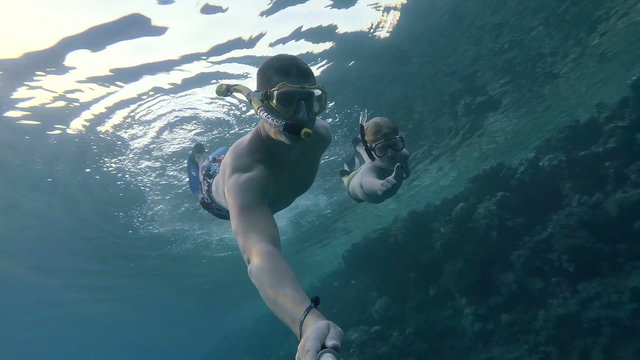 man with his son dives and makes selfe under water