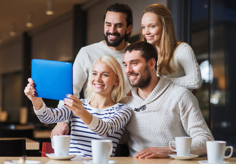 happy friends with tablet pc taking selfie at cafe