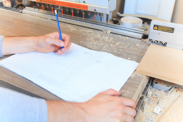 An adult carpenter measuring wood with ruler at table in