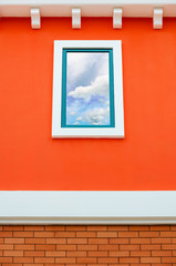 Sky reflection in window glass on orange wall