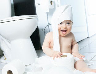 Toddler ripping up toilet paper in bathroom