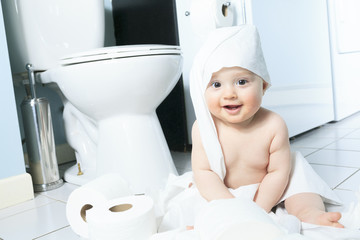 Toddler ripping up toilet paper in bathroom