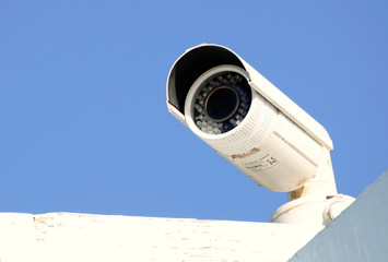 Security camera against bright blue sky.