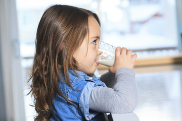 A Happy little child drinking milk on a kitchen