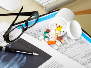 Doctor workplace. Pills, tablets, pen on patient history databas