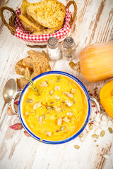 Homemade pumpkin soup in a tin bowl on rustic table