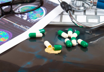 close-up green, white medical capsules, (one opened), on black b