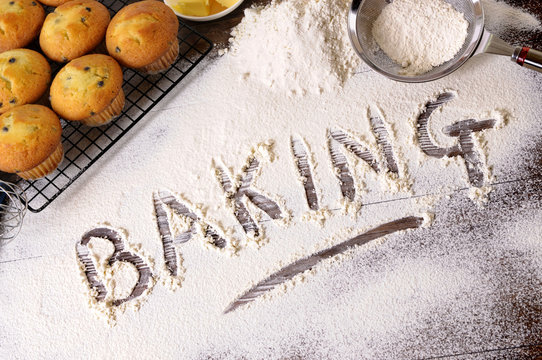 The word baking written in white flour with cup cakes muffin with ingredients photo