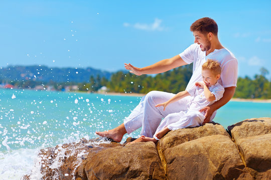 water splashing on happy father and son on vacation